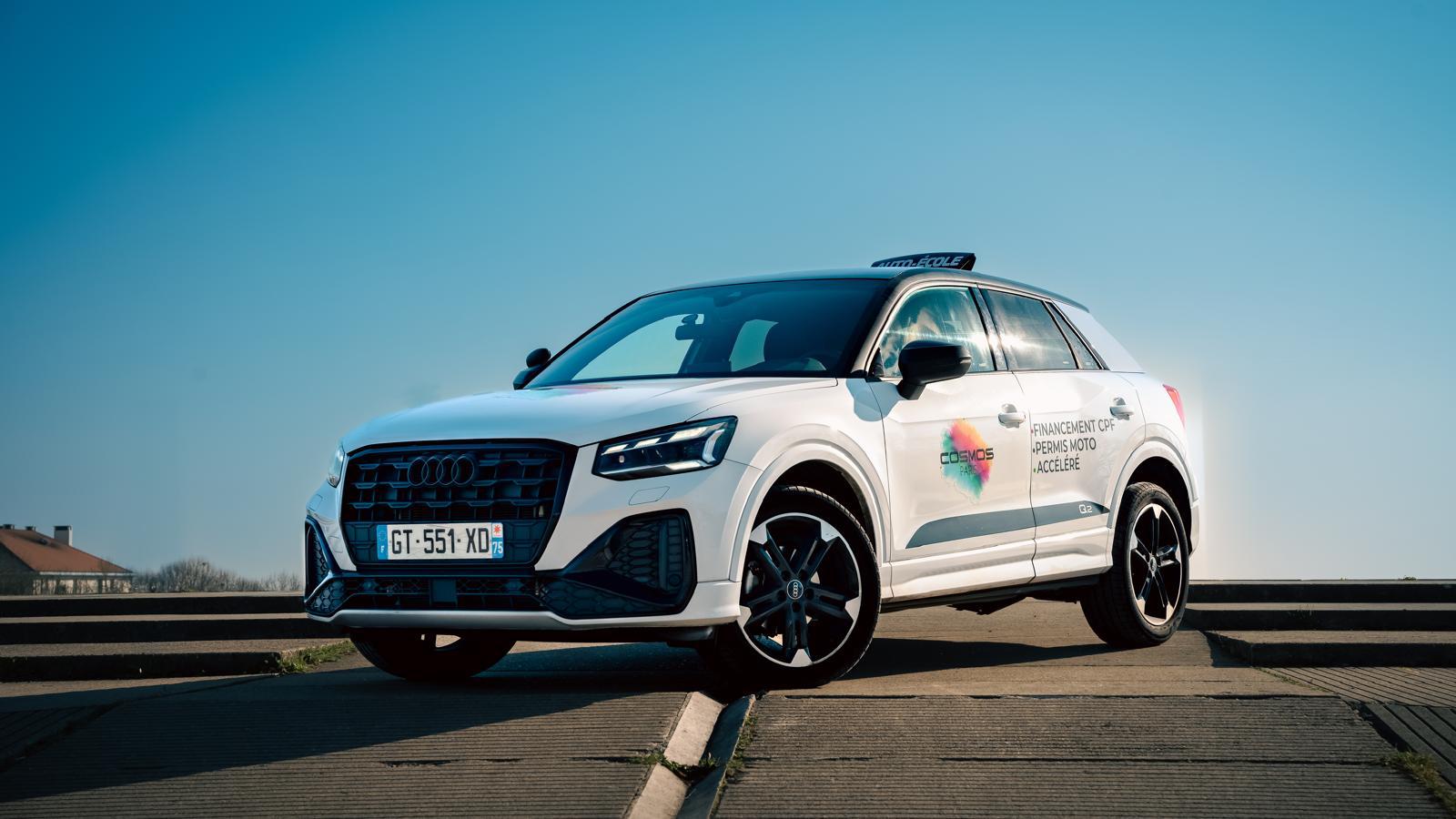 Audi Q2 blanche de l'auto-école Cosmos Paris devant un paysage parisien